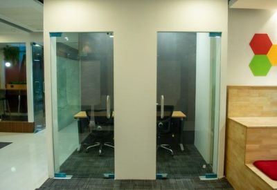 Private glass-enclosed workstations with ergonomic chairs and wooden accents.