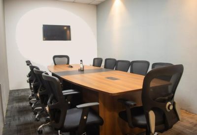 Professional meeting room featuring a wooden table, ergonomic black chairs, and a wall-mounted screen.