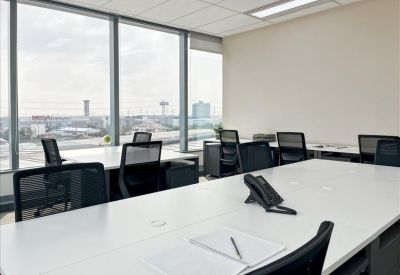 Bright coworking space featuring white desks, mesh back chairs, and large windows with city views.