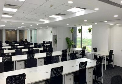 Spacious open-plan office with rows of white desks and ergonomic black chairs.