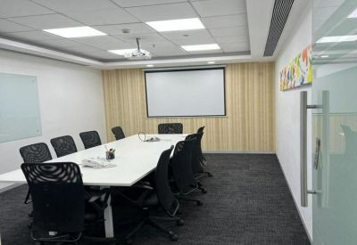 Professional meeting room featuring a white conference table, black mesh chairs, and a projection screen.