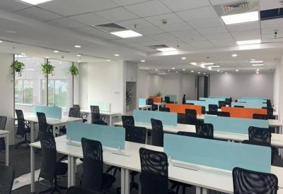 Modern workspace featuring white desks with light blue and orange privacy dividers.