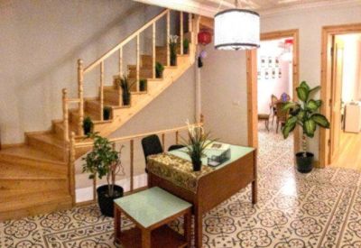 Reception area with wooden stairs, patterned tile flooring, and a reception desk.