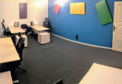Spacious office with a blue feature wall and multiple light wood desks.