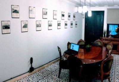 Meeting room with an oval wooden table and framed photos on a long white wall.
