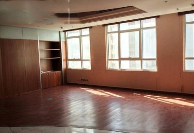 Spacious open-plan office with polished wood floors and large windows providing natural light.