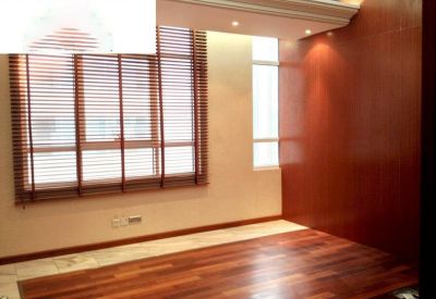 Interior room with wood-slat window blinds and dark wood flooring.