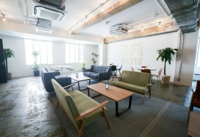 Sunlit lounge area featuring green and blue sofas around wooden coffee tables.