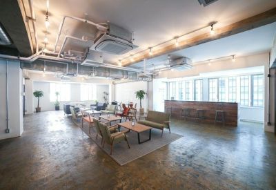 Spacious open-plan lounge with a wooden bar counter and polished concrete floors.