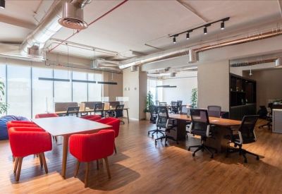 Spacious communal coworking area with large tables and vibrant red chairs.
