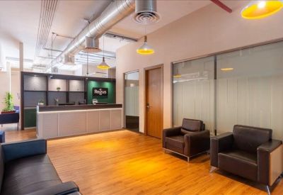Contemporary reception area with wooden flooring, warm lighting, and a grey front desk.
