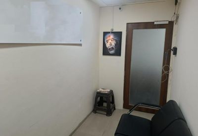 Waiting area with a black sofa, small stool, and a framed portrait on the wall.