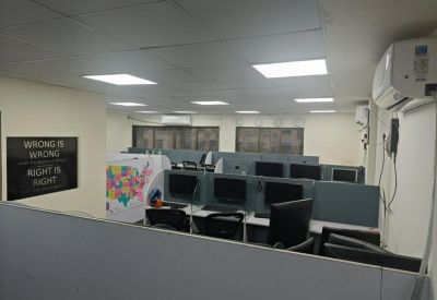 Modern office cubicles with computer monitors and motivational wall signage.