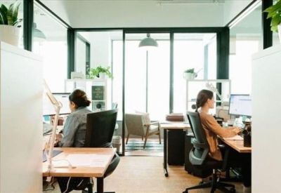 Modern open-plan office space with glass partitions and employees working at desks.