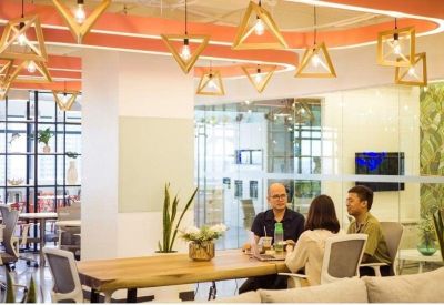 Modern breakout area featuring wooden pendant lights and a large communal table.