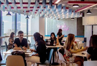 Busy open-plan office with unique ceiling baffle design and large windows for natural light.