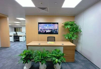 Reception desk with vibrant potted plants and a wall-mounted digital display.