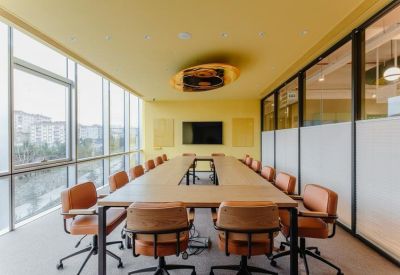Modern boardroom with a U-shaped table, leather chairs, and large windows.