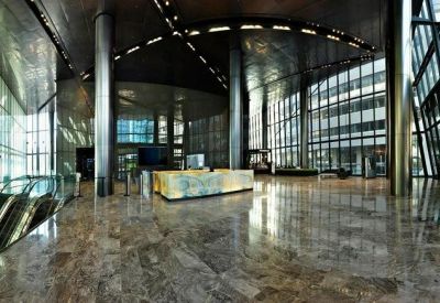 Expansive modern building lobby with polished marble floors and tall glass walls.