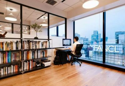 Bright workspace featuring a desk by a window with city views and a glass-partitioned library wall.