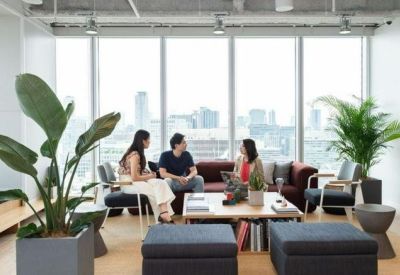 Lounge area with plush seating, potted plants, and large windows overlooking the city skyline.