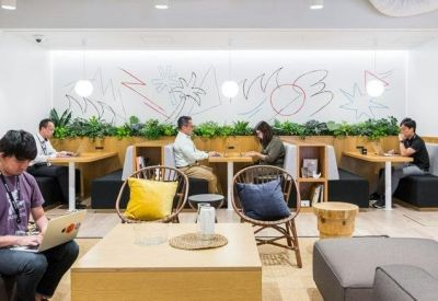 Modern communal lounge with a large illustrated mural, indoor plants, and comfortable seating areas.
