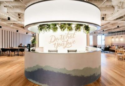 Bright reception area featuring a circular desk with greenery and a neon sign reading Do What You Love.