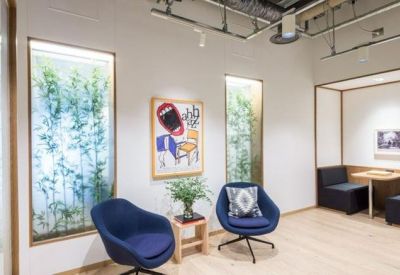Lounge area with blue swivel chairs, vibrant pop art, and bamboo plants visible through tall windows.