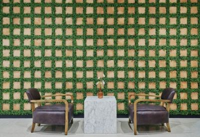 Lounge area with two leather armchairs and a marble side table against a green lattice feature wall.