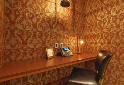 Private phone booth or study nook with damask wallpaper and a dark leather chair.