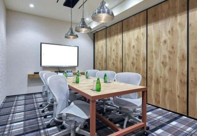 Bright meeting room with a light wood table, mesh chairs, and industrial pendant lights.