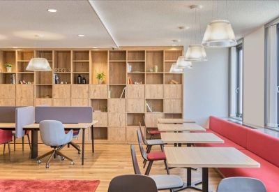 Bright communal break area with wood shelving, a red sofa, and cafe-style seating.