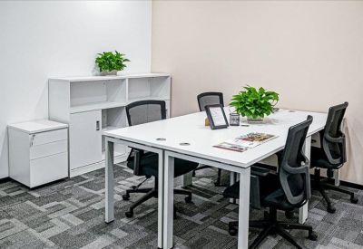 Modern four-person workstation area with white desks, black chairs, and a white storage cabinet.