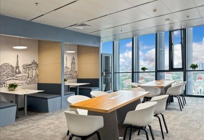 Bright communal lounge with wood-topped tables, modern white chairs, and floor-to-ceiling windows.