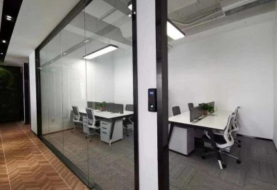 Glass-walled private office suite with white desks and ergonomic chairs.