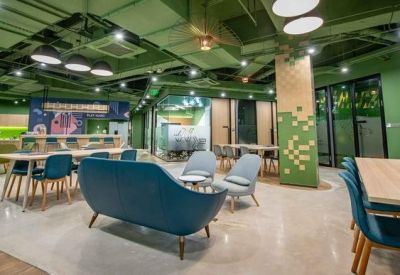 Spacious communal lounge with green ceilings, modern sofas, and dining tables.