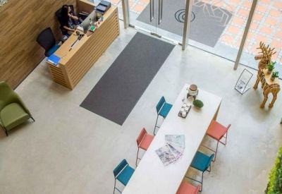 High-angle view of a bright reception lobby with a living green wall and colorful chairs.