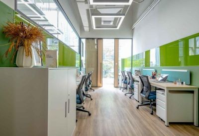 Sleek office corridor with white desks, ergonomic chairs, and vibrant green accent walls.