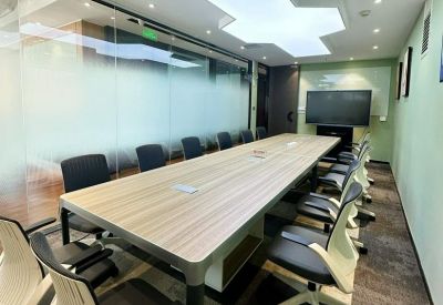 Bright conference room with a long wooden table and geometric ceiling light.