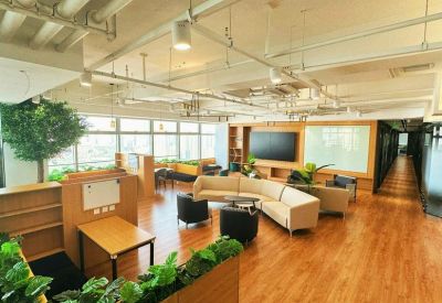Modern open-plan common area with wooden flooring and a large TV screen.