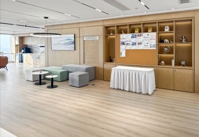 Contemporary breakout lounge with modular grey seating, wood-paneled walls, and a white-skirted table.