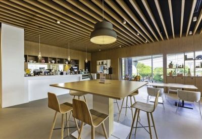 Stylish modern café area with wooden slatted ceilings, pendant lighting, and high-top tables.