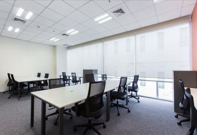 Spacious open-plan workspace featuring multiple white desks and ergonomic black chairs.
