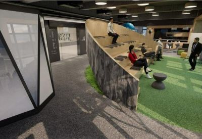 Modern communal area with tiered wooden seating and green artificial turf flooring.