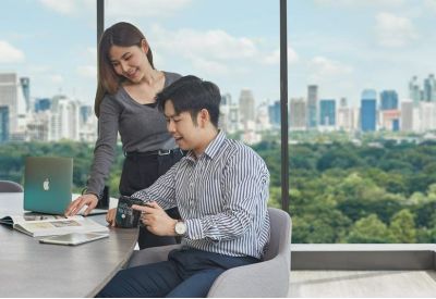 Two people collaborating at a table overlooking a lush park.