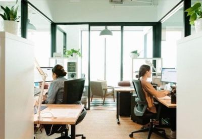 Private office with two desks and large glass partitions.