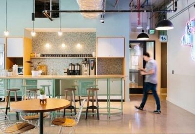 Bright kitchen area with bar stools and coffee machines.