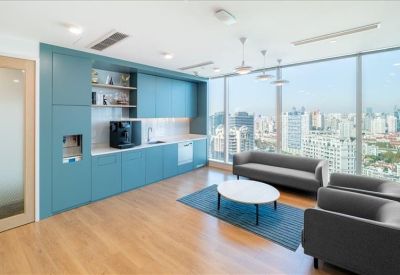 Communal break area with a blue kitchen unit, lounge seating, and city views.