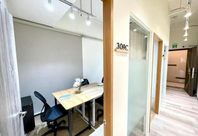 Glass-walled small meeting room with a wooden table and blue office chairs.