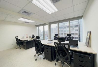 Bright multi-desk office space with black ergonomic chairs and large windows.